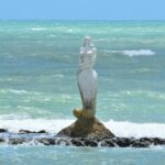 photo of a mermaid sculpture in the middle of the ocean
